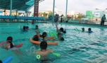 Các huấn luyện viên tập bơi cho các em học sinh.