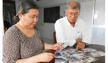 Vợ chồng ông Nguyễn Văn Xiếu xem những tấm ảnh gia đình sum họp, hạnh phúc.
