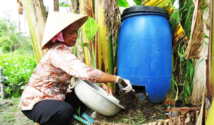 Chị Trang lấy phân hữu cơ từ thùng ủ rác compost.