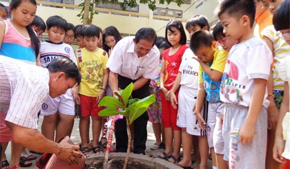 TS. Phạm Văn Khanh cùng các học sinh trường Tiểu học Thiên Hộ Dương trồng cây trước sân trường.