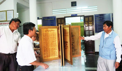 Ông Võ Văn Hải (bên phải) giới thiệu sách bằng gỗ về AHDT Nguyễn Hữu Huân tại buổi kiểm định nội dung.