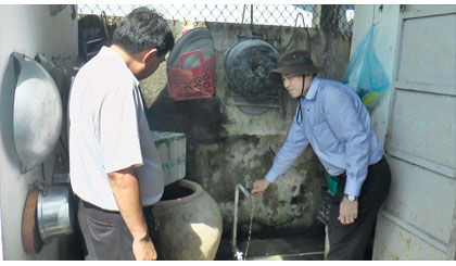 Chủ tịch UBND tỉnh Lê Văn Hưởng kiểm tra nước sinh hoạt tại một hộ dân ở ấp Phú Hữu, xã Phú Tân.