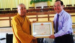 Phó Chủ tịch UBND tỉnh Trần Thanh Đức và Hòa thượng Thích Huệ Minh, Trường Ban Trị sự Phật giáo tỉnh trao xe lăn và quà tặng cho nạn nhân chất độc da cam bị khuyết tật vận động.