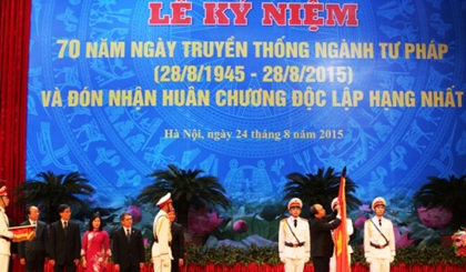 Phó Thủ tướng Nguyễn Xuân Phúc gắn Huân chương Độc lập Hạng nhất lên cờ Truyền thống của Ngành Tư pháp. (Ảnh: TH).