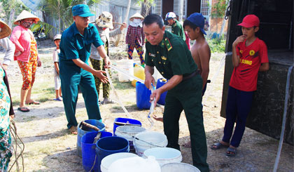 Thiếu tá Nguyễn Hữu Nhâm chuyển nước sạch phục vụ bà con.